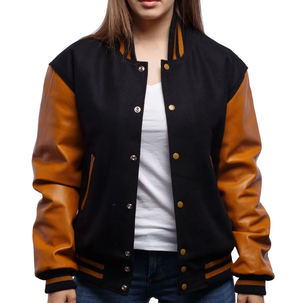 A woman wearing a black and orange varsity jacket with leather sleeves and wool body, buttoned at the front with metal buttons, standing against a white background.