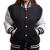 A woman wearing a black and white varsity jacket with leather sleeves and wool body, featuring a button-up front and side pockets.