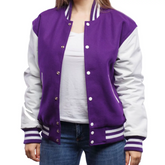 A woman wearing a purple and white varsity jacket with leather sleeves and wool body, buttoned up with metal buttons.