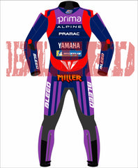 Back view of the Prima Pramac Yamaha MotoGP 2025 racing suit for rider Jack Miller, displaying prominent sponsor logos such as Prima on the chest and back, along with Alpine, Pramac, Yamaha, and the newly added "BLEED" logo on the arms and legs. The suit is primarily blue with red and purple accents. The back of the suit clearly shows the rider name "MILLER"