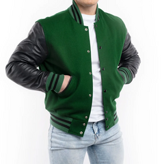A man wearing a green and black varsity jacket with leather sleeves and white t-shirt, standing in front of a white background.