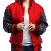 A woman wearing a red varsity jacket with leather sleeves and white t-shirt, standing against a white background.