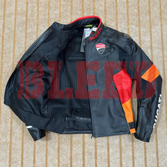 Top-down view of a Ducati Corse C6 motorcycle jacket in black and orange leather, partially unzipped to reveal the breathable mesh inner lining. The jacket features official Ducati branding, including the Ducati logo on the chest and sleeves, with the Italian flag detail on the collar. The jacket is laid flat on a beige carpet, showcasing its high-quality materials and race-inspired design.