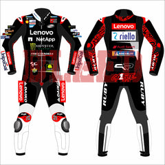 Francesco Bagnaia Ducati Motorcycle Riding Suit BritishGP 2024. The suit is predominantly black with red and white accents, featuring sponsor logos such as Lenovo, NetApp, Monster Energy, and Riello. The front view shows the suit with a central zipper, while the back view displays prominent branding at the top. Matching gloves and boots in white with red detailing complete the ensemble