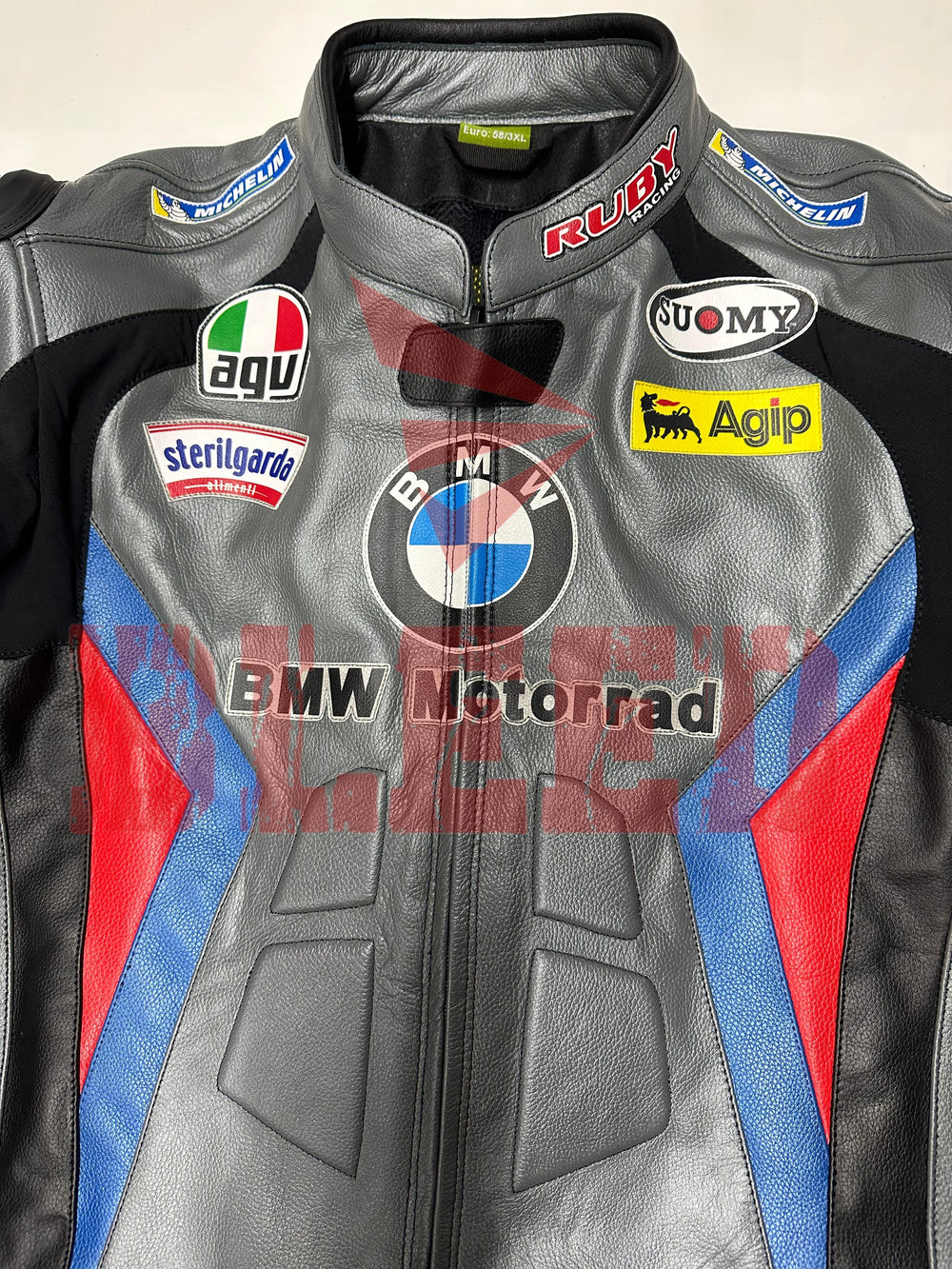 Front view of the BMW Motorrad Racing Motorcycle Jacket in gray with black, blue, and red detailing. The jacket displays prominent sponsor logos and is crafted from premium leather, ideal for motorbike riders seeking style and protection
